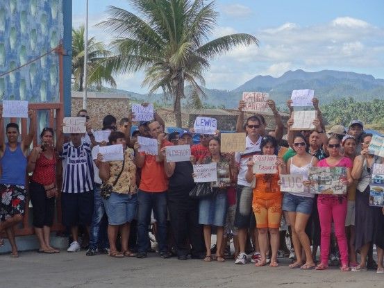 Cuba- Baracoa des personnes attendent avec panneaux pour les Casa Particular photo blog voyage tour du monde https://yoytourdumonde.fr