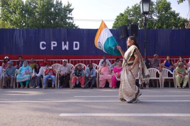 Une femme indienne avec un drapeau indien le long de la frontiere pakistanaise à Amristar en Inde photo blog voyage tour du monde https://yoytourdumonde.fr
