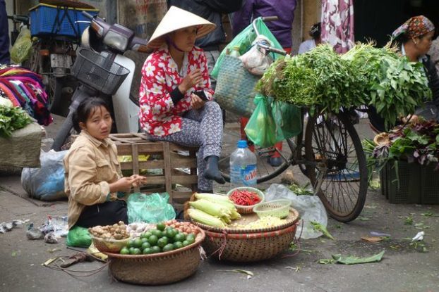 Hanoi-Vietnam: Vendeurs coiffes du chapeaux coniques vendent leurs marchandises. Regardez le velo....